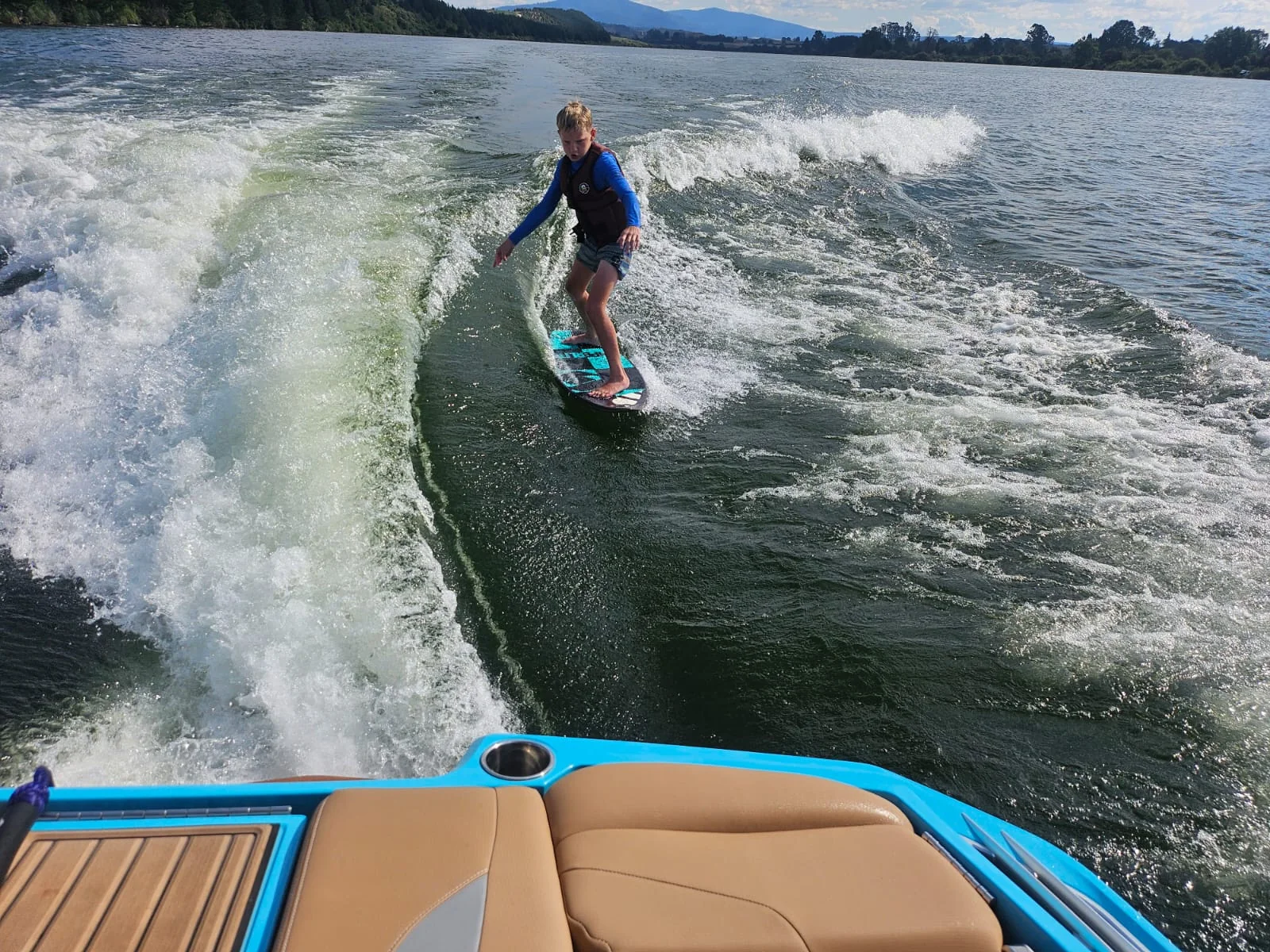 Young wakesurfer progressing behind the boat