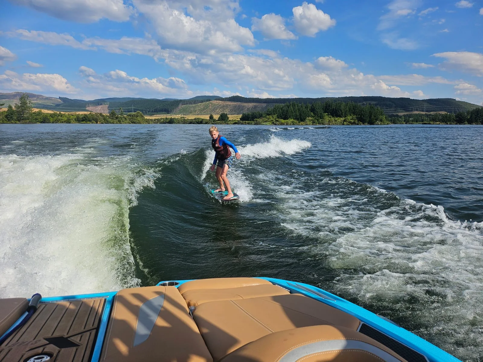 Wakesurfer with Lake Maraetai in the background